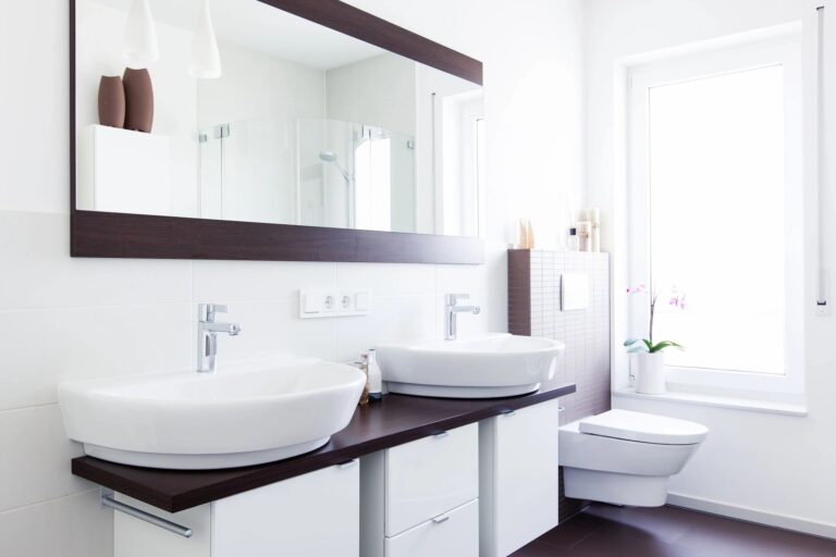 a bathroom with two sink and cabinets