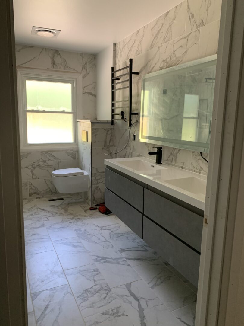 A bathroom with white marble tiles and a sink.