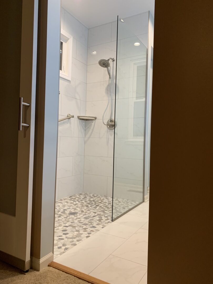 A bathroom with a glass shower stall and tiled floor.