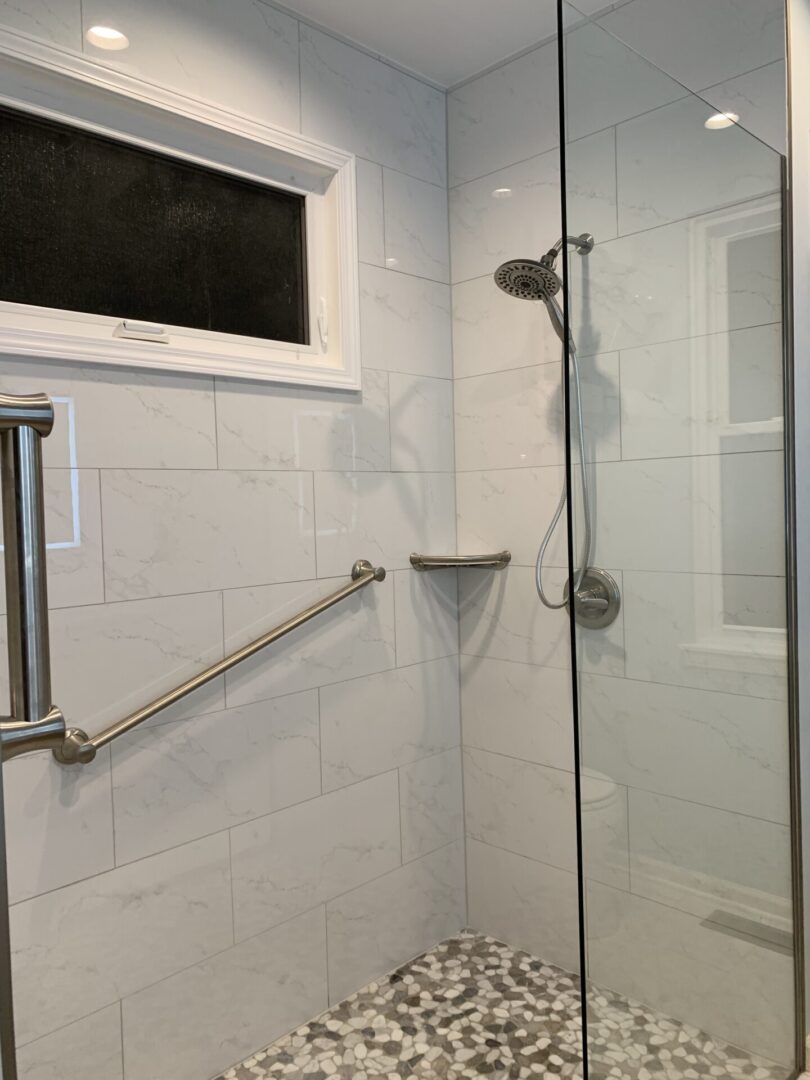 A bathroom with a glass shower stall and a window.