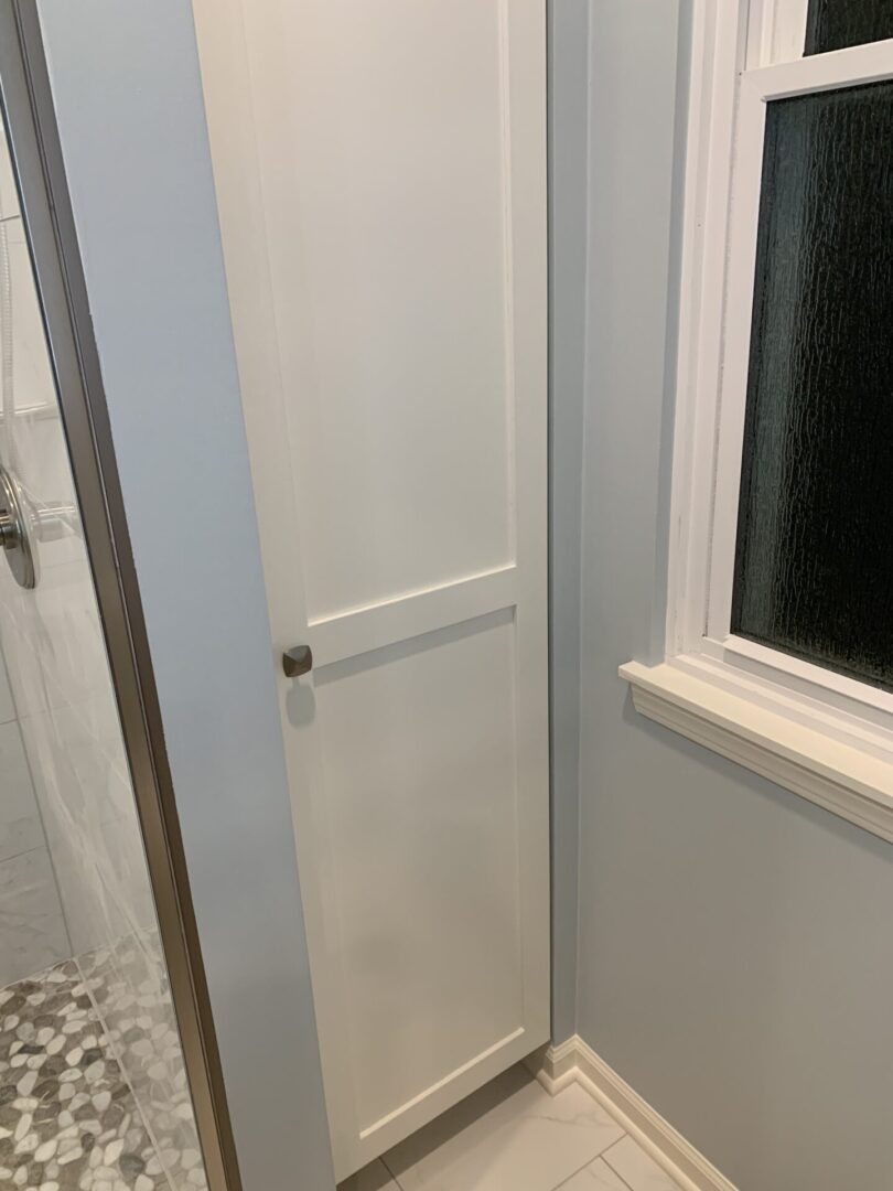 A bathroom with a window and a white cabinet.