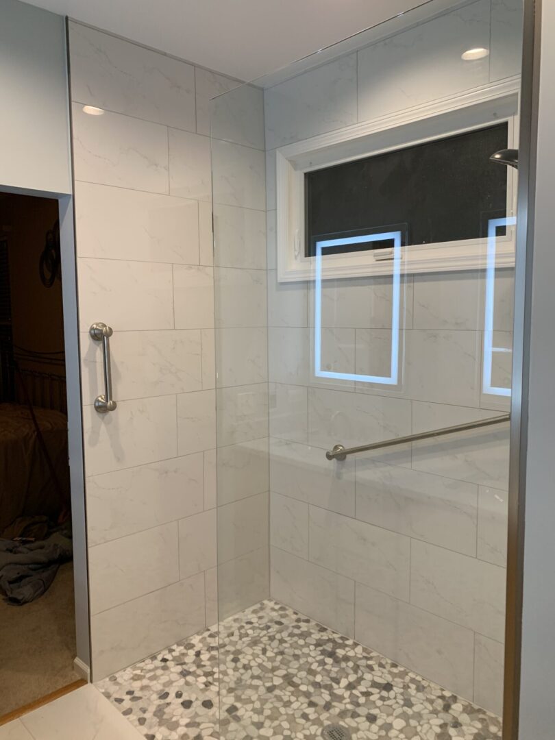 A bathroom with a glass shower door and a window.