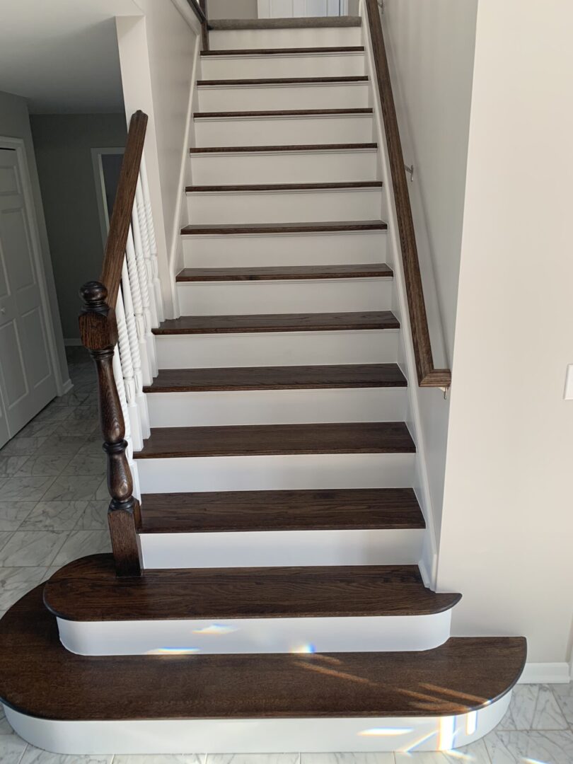 A stairway with wood treads and a white railing.
