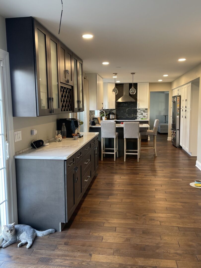 A kitchen with hardwood floors and a cat laying on the floor.