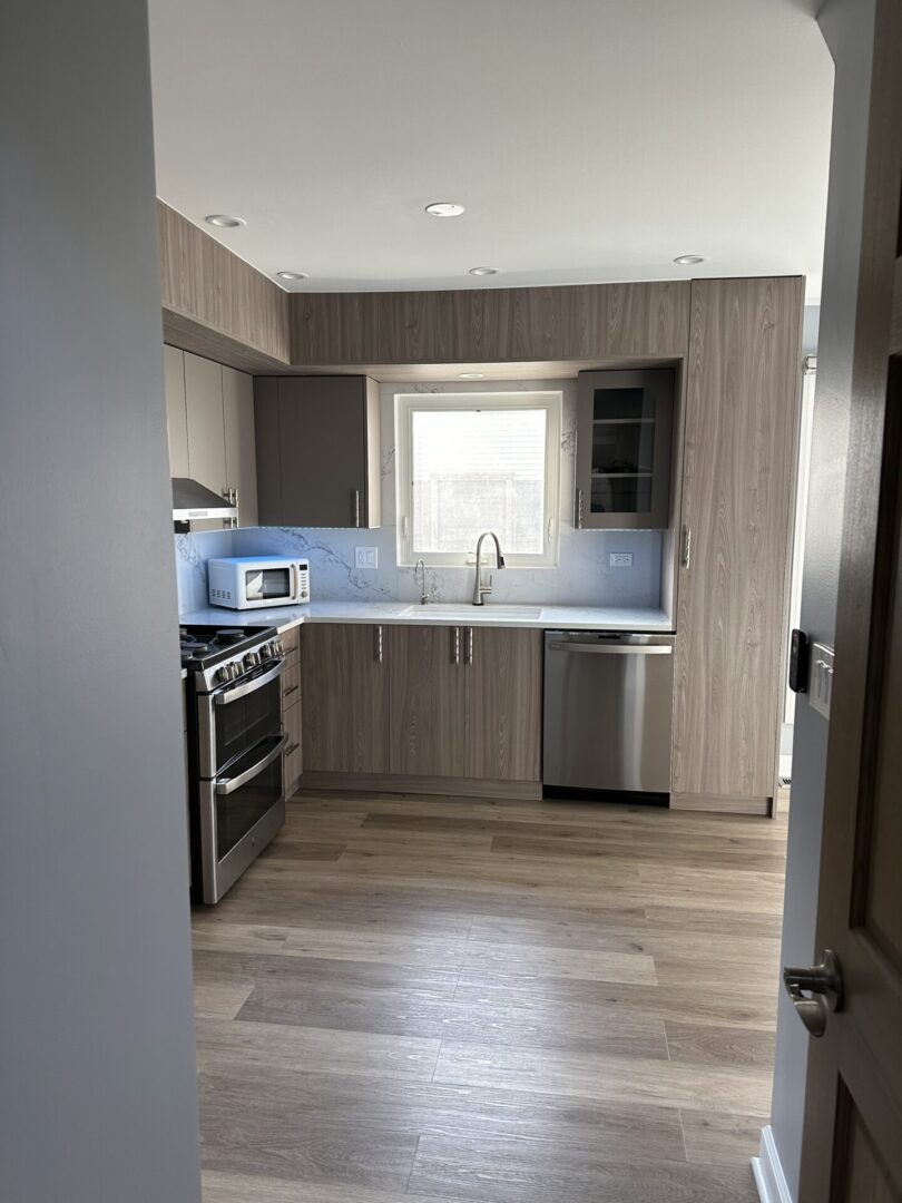 A kitchen with stainless steel appliances and wood floors.