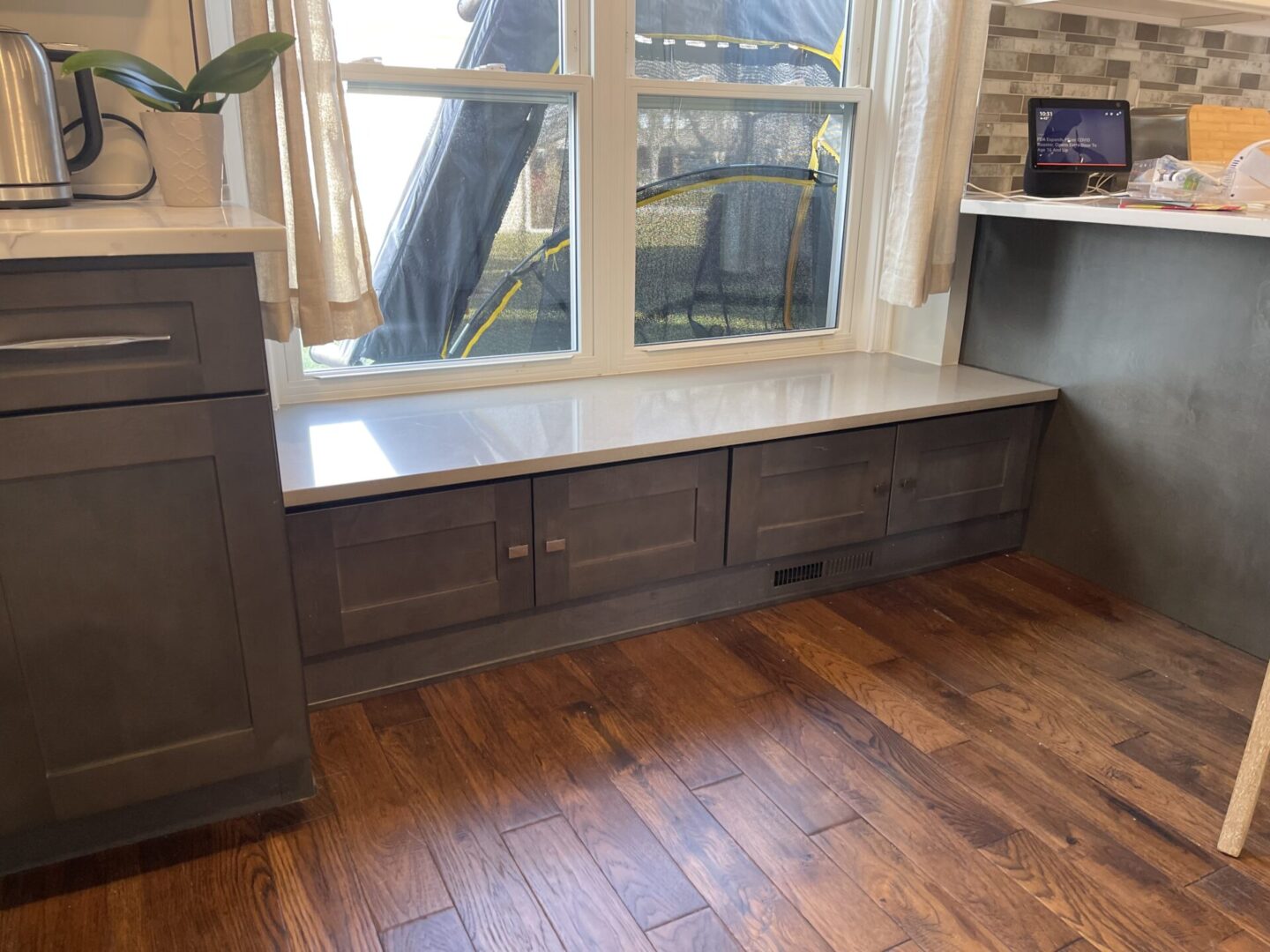 A window seat in a kitchen with gray cabinets.