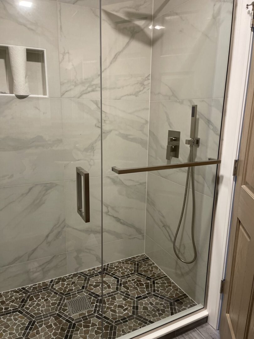 A bathroom with a glass shower door and tiled floor.