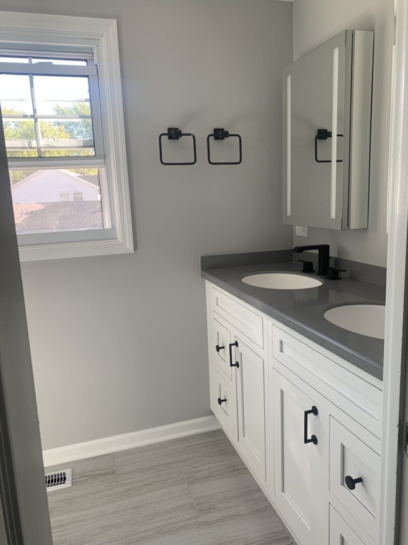 A bathroom with white cabinets and gray counter tops.