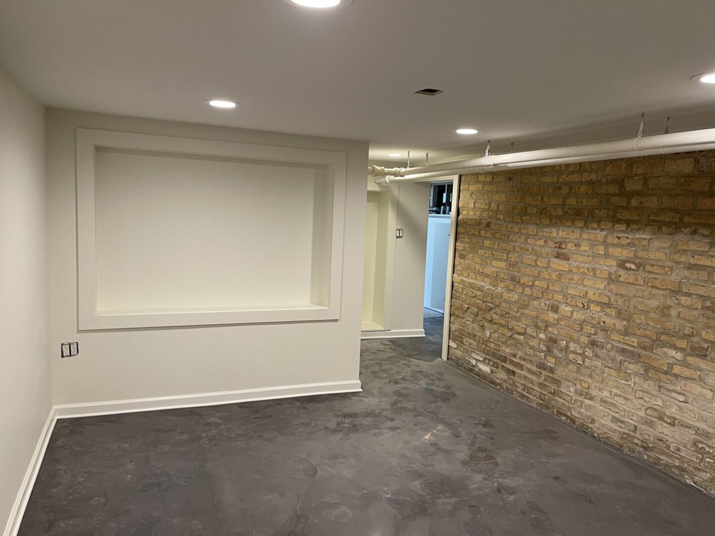 An empty room with a brick wall and concrete floor.