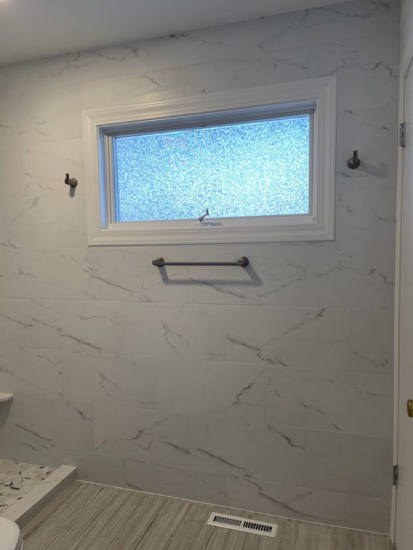 A bathroom with white tile and a window.