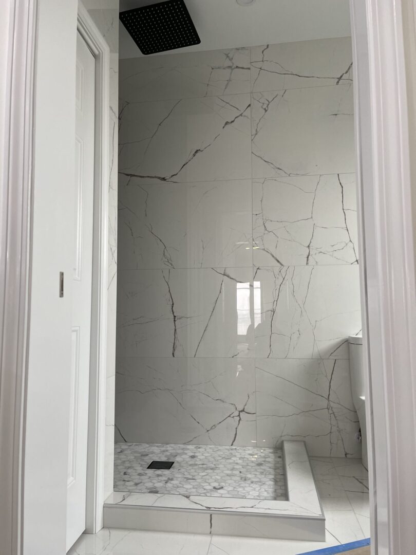 A white bathroom with a marble floor and shower.