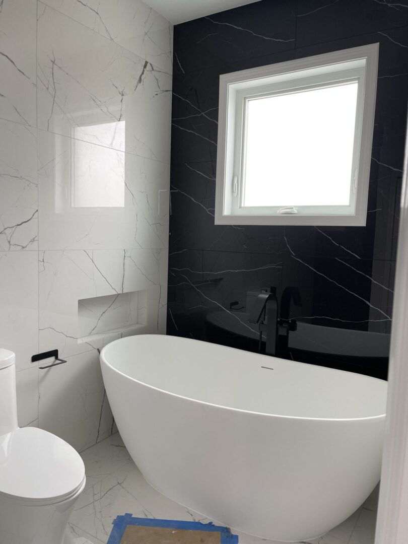 A black and white bathroom with a bathtub and toilet.