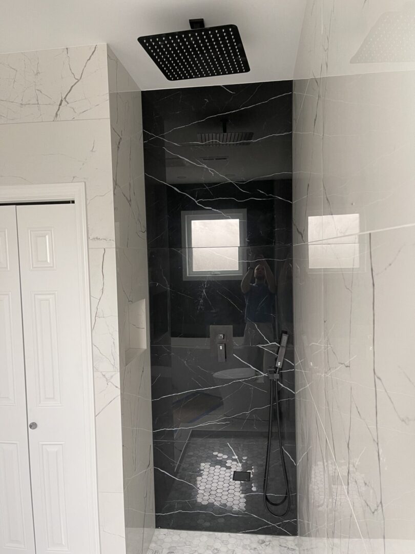 A black and white marble shower with a shower head.