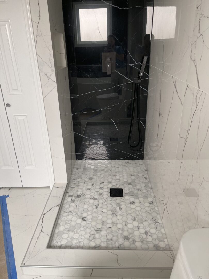 A bathroom with a black and white marble shower.