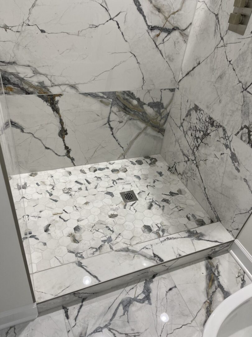 A bathroom with a marble floor and shower.
