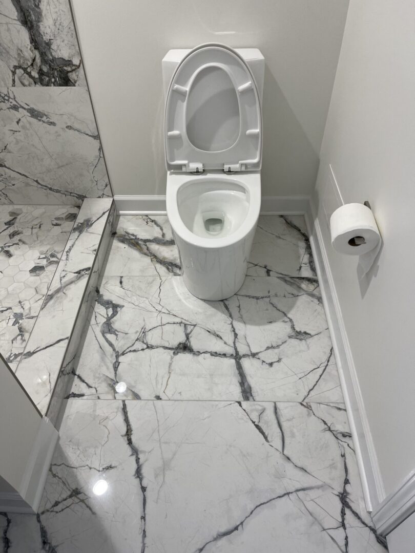 A bathroom with a white toilet and marble floor.