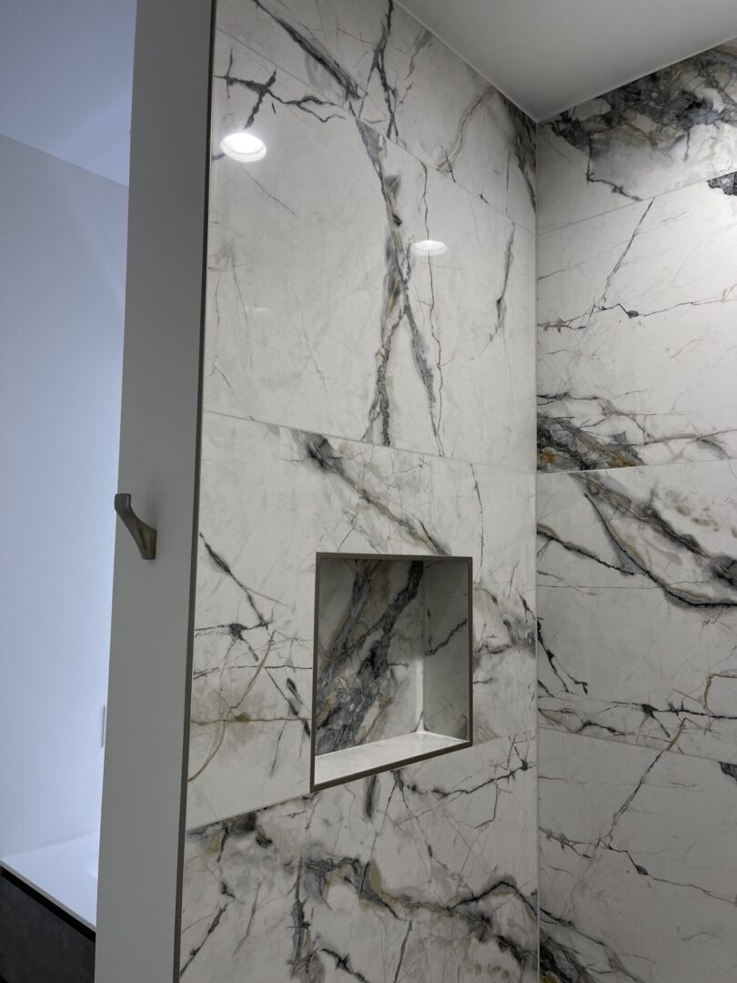 A bathroom with a marble shower wall.
