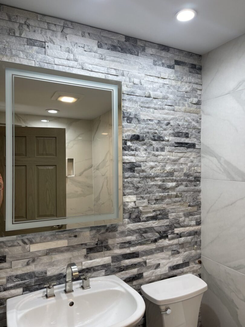 A bathroom with a marble wall and sink.